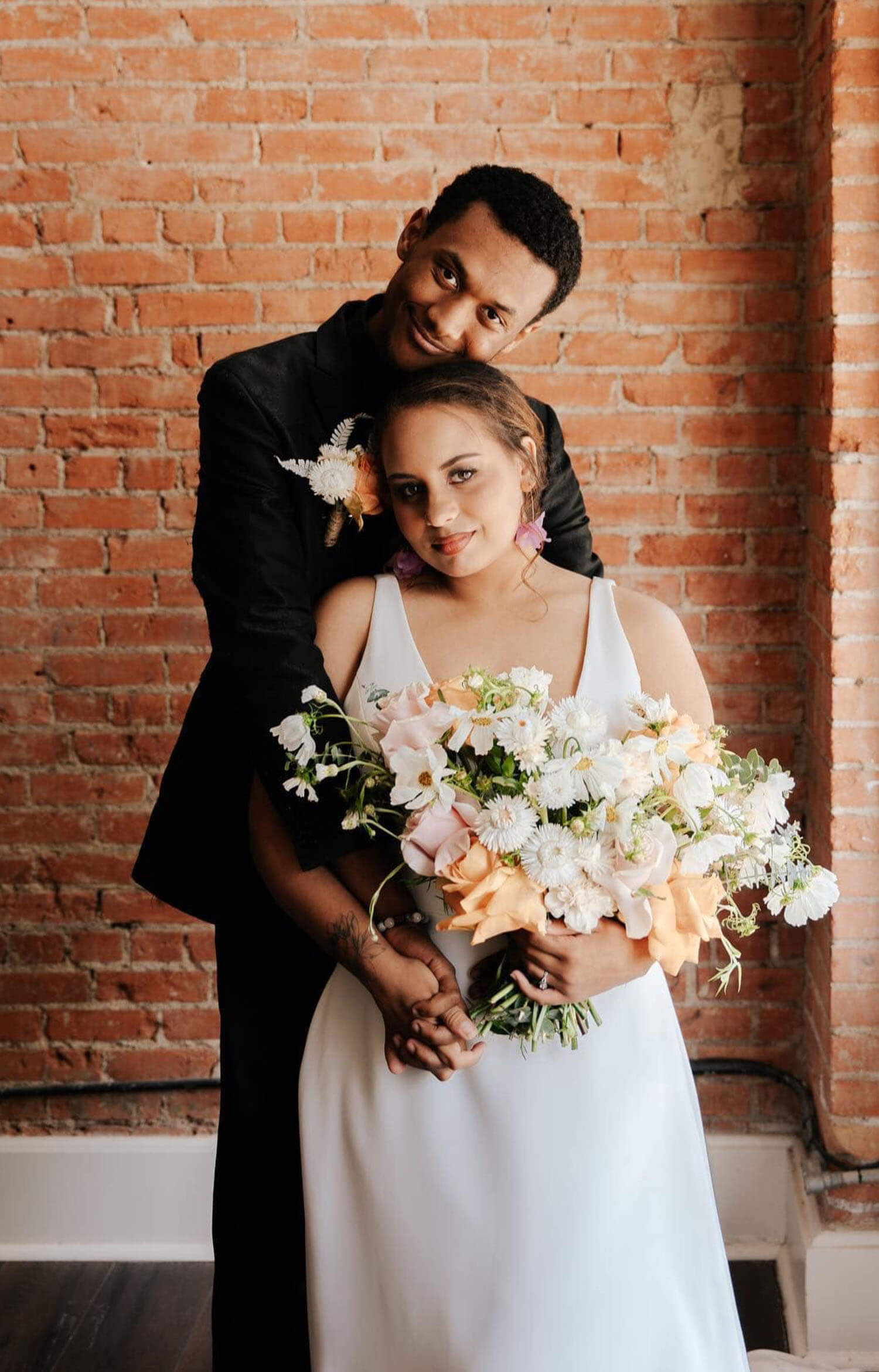 Сouple wearing a white gown and a black suit. Mobile image